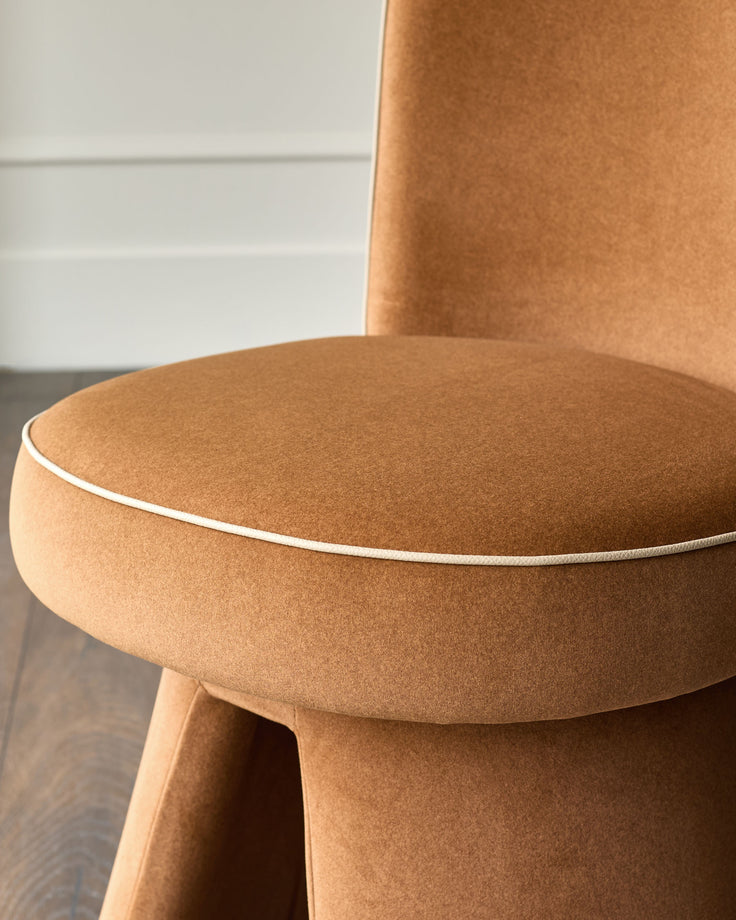 Jenna swivel dining chair in caramel fabric, showing curved seat with piping detail and cylindrical base.