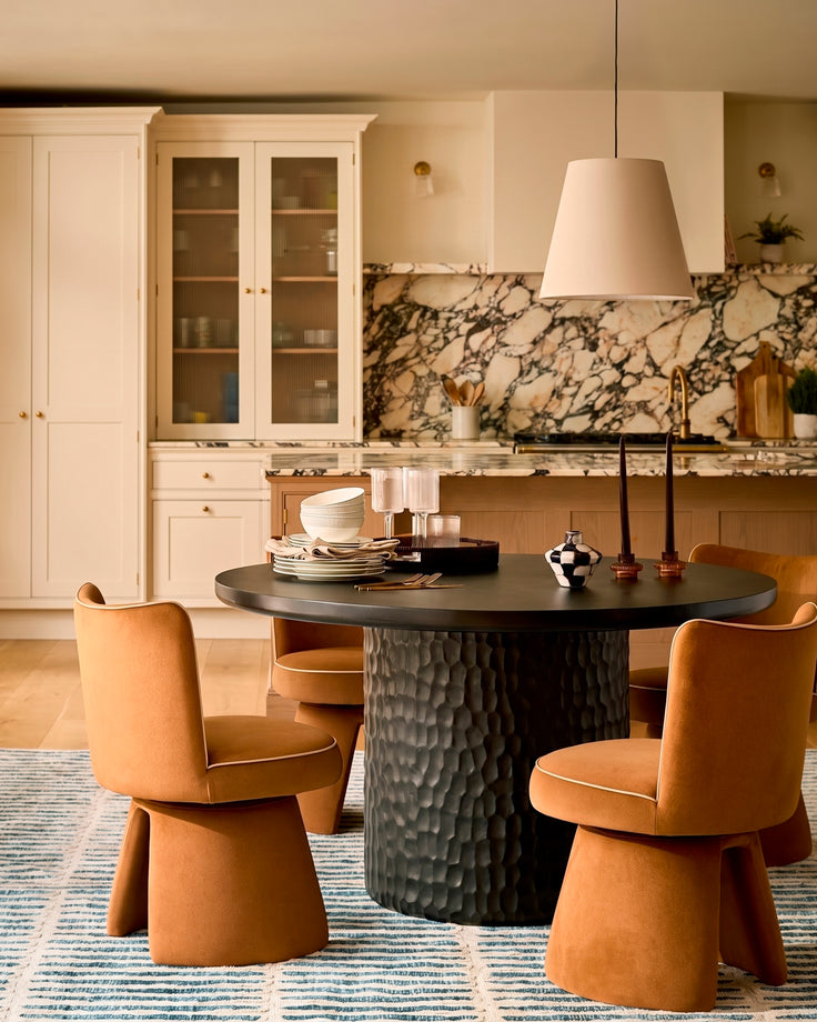 Jenna swivel dining chair in caramel fabric, shown in a modern kitchen setting around a black round table.