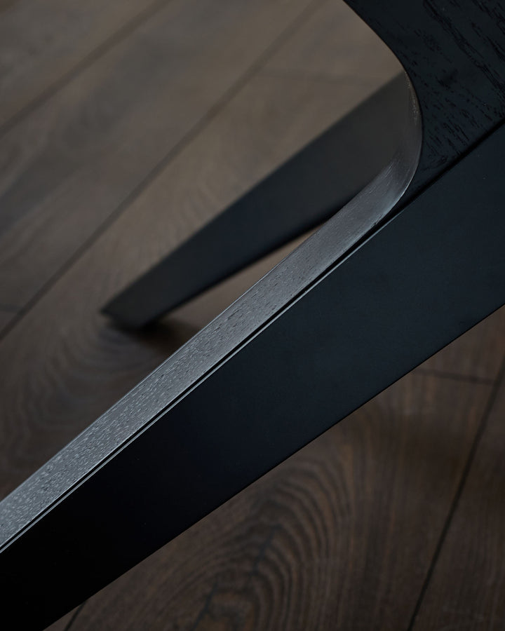 Black handle detail on extending dining table with brushed metal finish and dark wood surface.