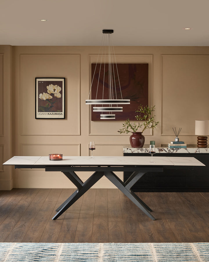 Jennet extending dining table in white ceramic with black X-frame base, shown extended in modern dining room setting.