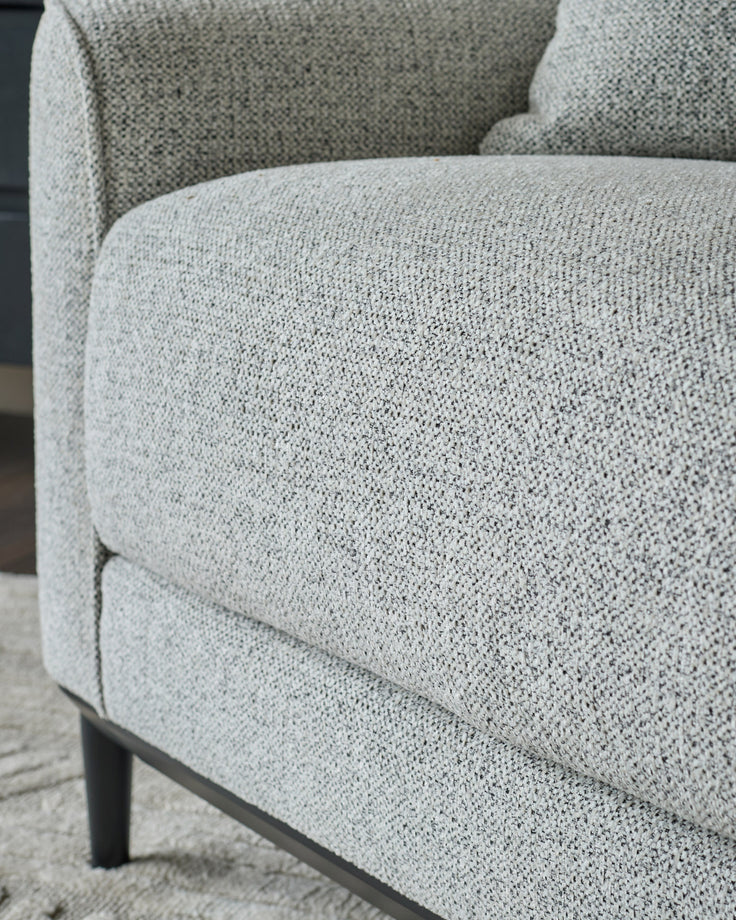 Grey fabric armchair with textured upholstery and dark wooden legs, shown in close-up detail.