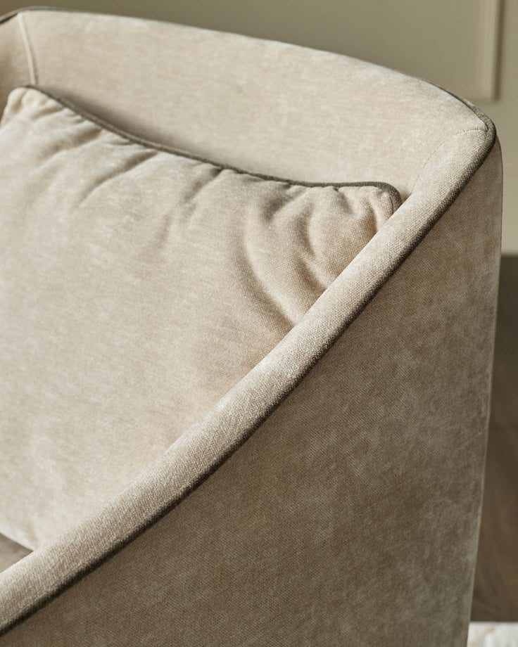 Julep dining chair in champagne fabric, close-up of curved armrest and seat detail showing upholstery texture.