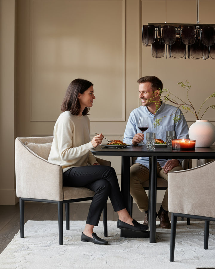 Champagne fabric dining chair with curved back and black metal legs, shown in lifestyle setting.