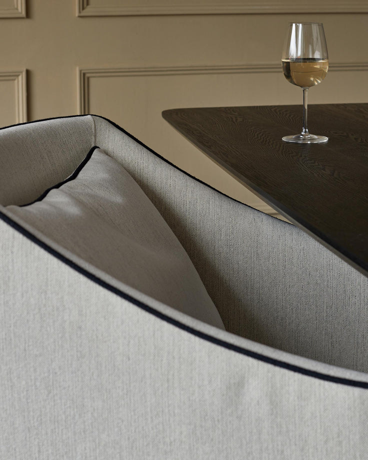 A chair and dark wood table set with a white wine glass, showcasing elegant furniture design.