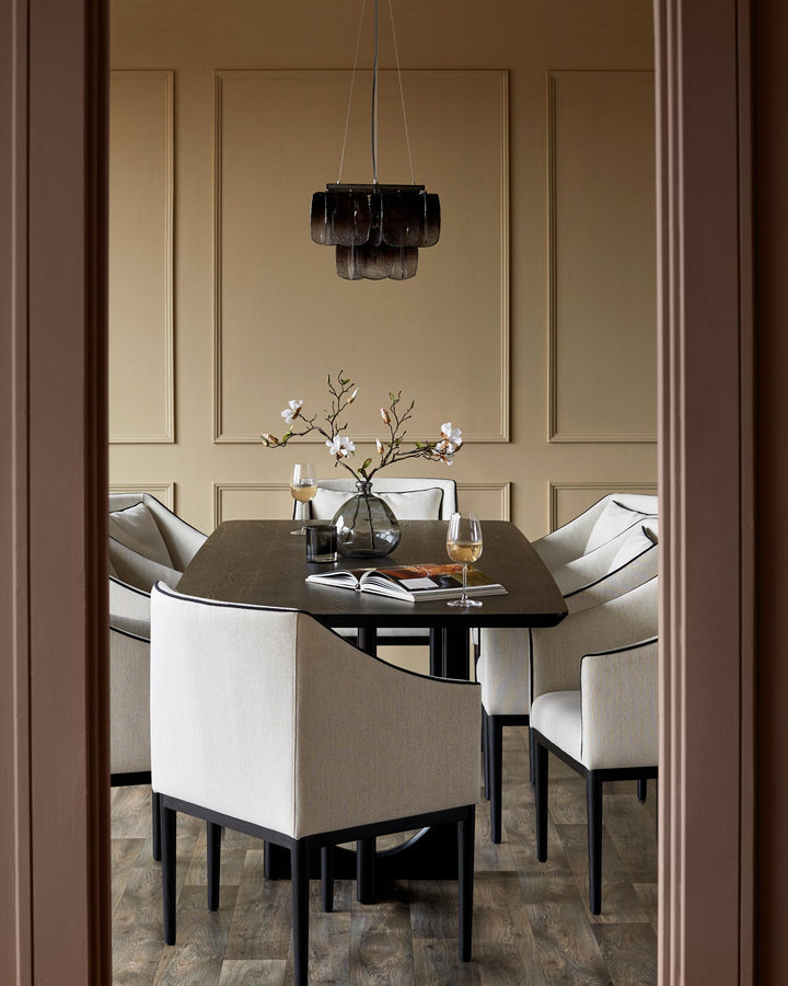 Dining room with six upholstered chairs around a dark wood table. Statement chandelier overhead. Stylish and inviting design.