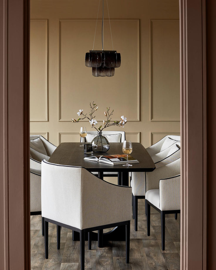 Dining room with six upholstered chairs around a dark wood table. Statement chandelier overhead. Stylish and inviting design.