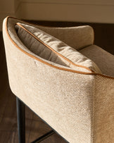 Julep bar stool in honey fabric, angled side view showing curved backrest and leather trim detail.