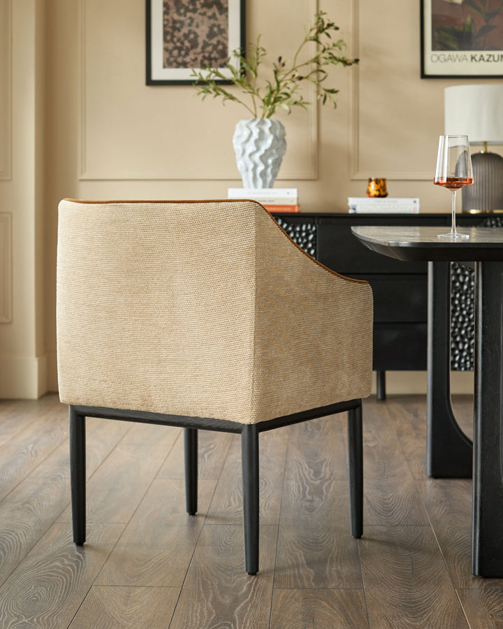 Julep dining chair in honey fabric with black wooden frame, shown at table in modern dining room setting.
