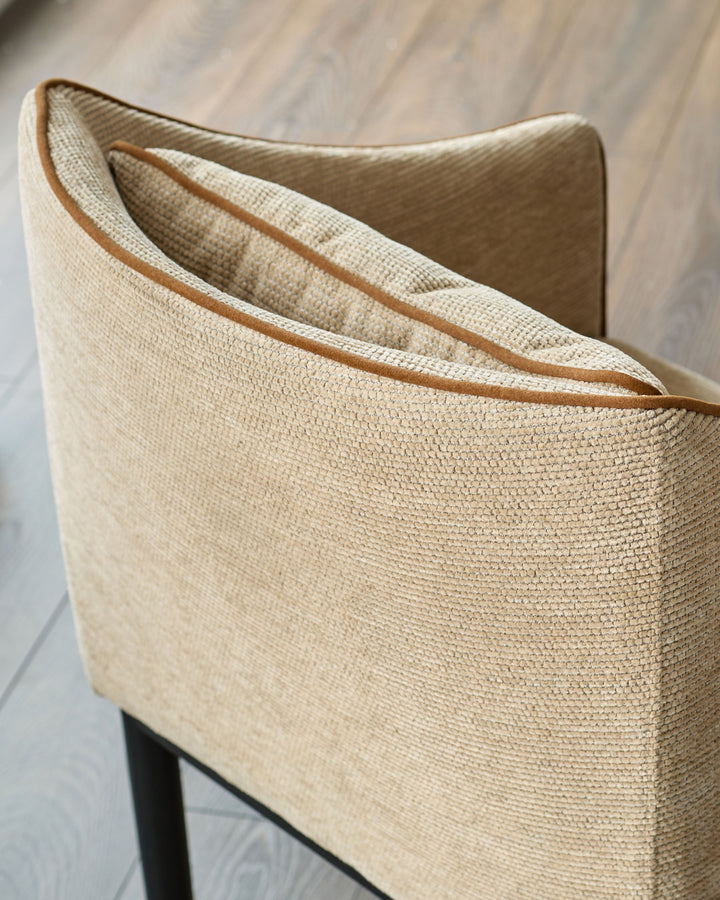 Julep dining chair in honey fabric, close-up of curved backrest with tan leather trim detail.