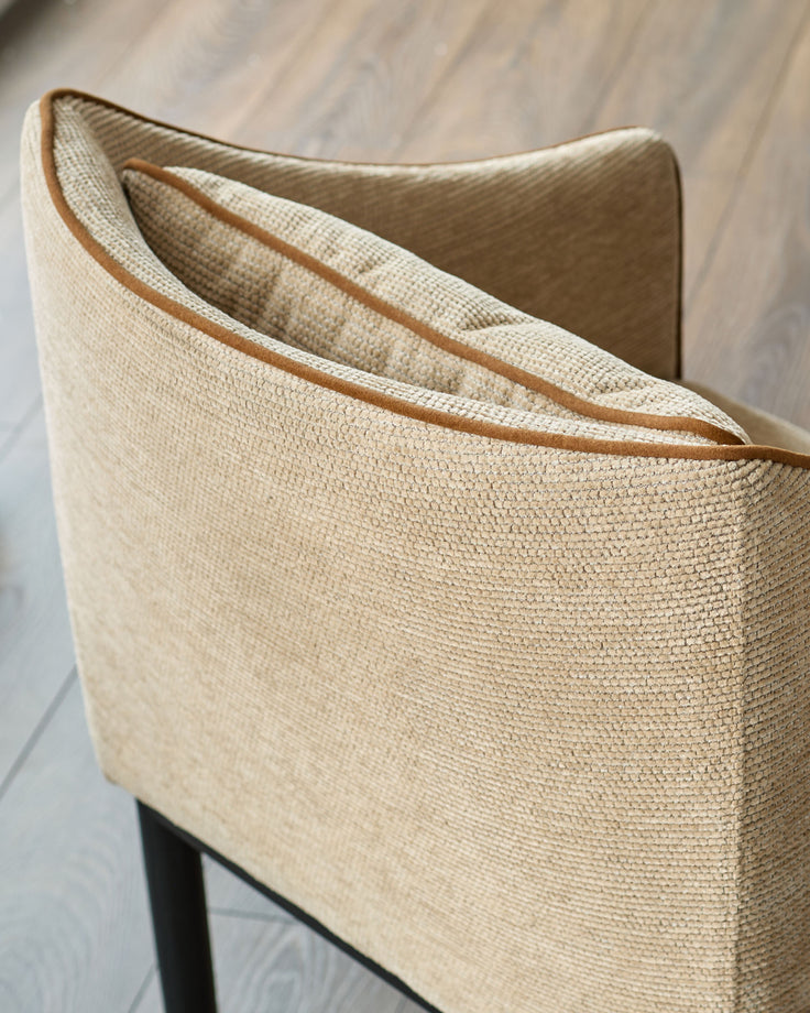 Julep dining chair in honey fabric, close-up of curved backrest with tan leather trim detail.