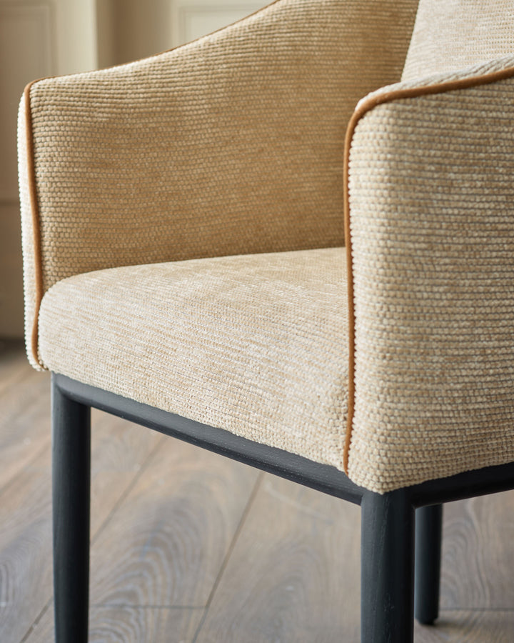 Julep dining chair in honey fabric, angled view showing textured upholstery and dark wood legs.