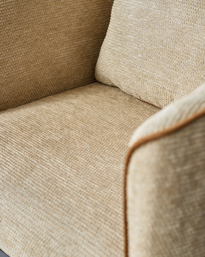 Close-up of honey-colored fabric upholstery on Julep dining chair, showing textured weave and wooden frame detail.