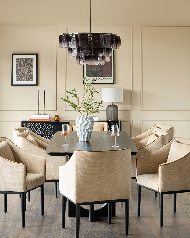 Honey-colored fabric dining chair with black legs, shown in an elegant dining room setting around a round table.