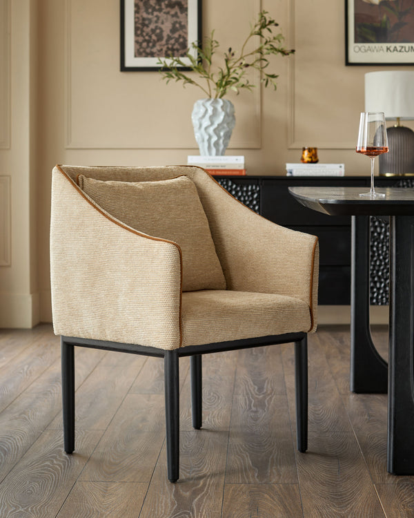 Honey fabric dining chair with black metal legs, shown in a modern beige room setting next to a black table.
