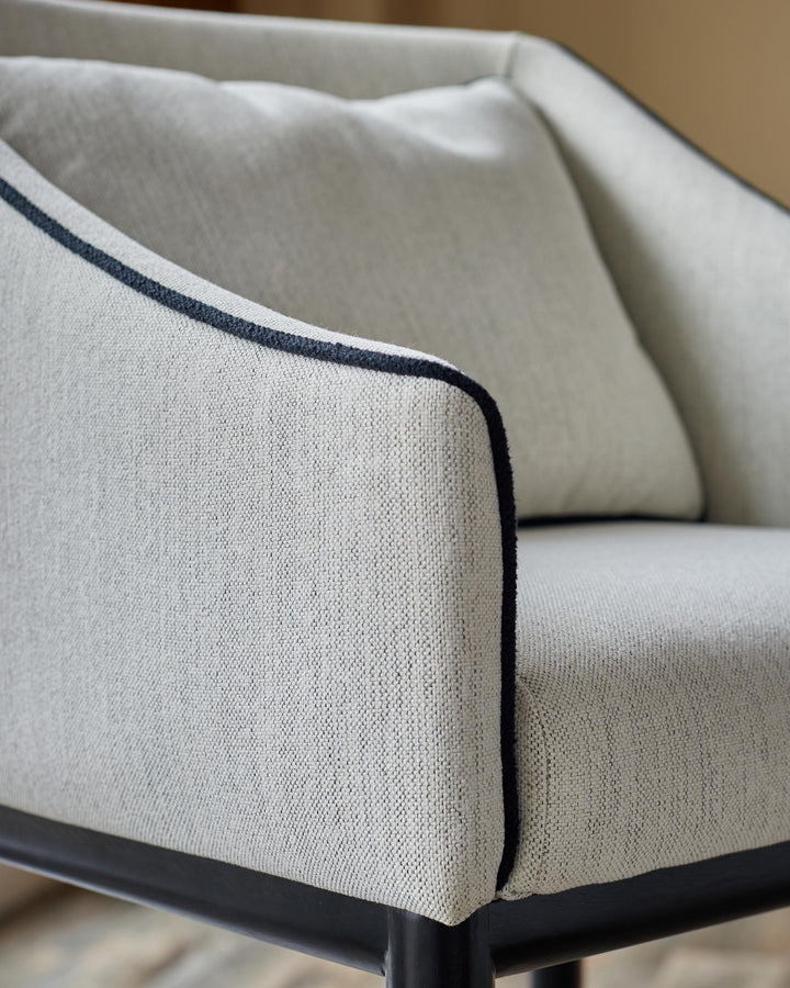 Close-up of a chair with light grey upholstery and black trim and frame, showcasing its texture and design.