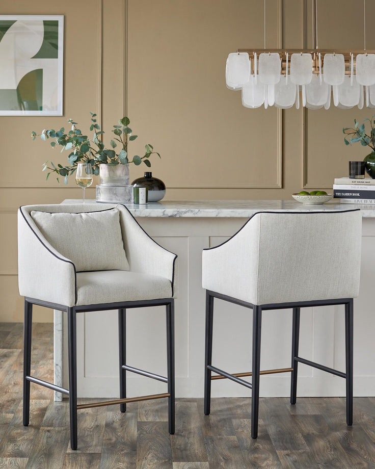 Two stylish bar stools with light upholstery, dark metal frames, and sleek design.