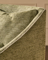 Close-up of olive green upholstered bar stool showing textured fabric weave and piping detail along the arm.