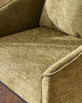 Olive green upholstered chair seat and back with textured fabric weave and dark wooden frame detail visible.
