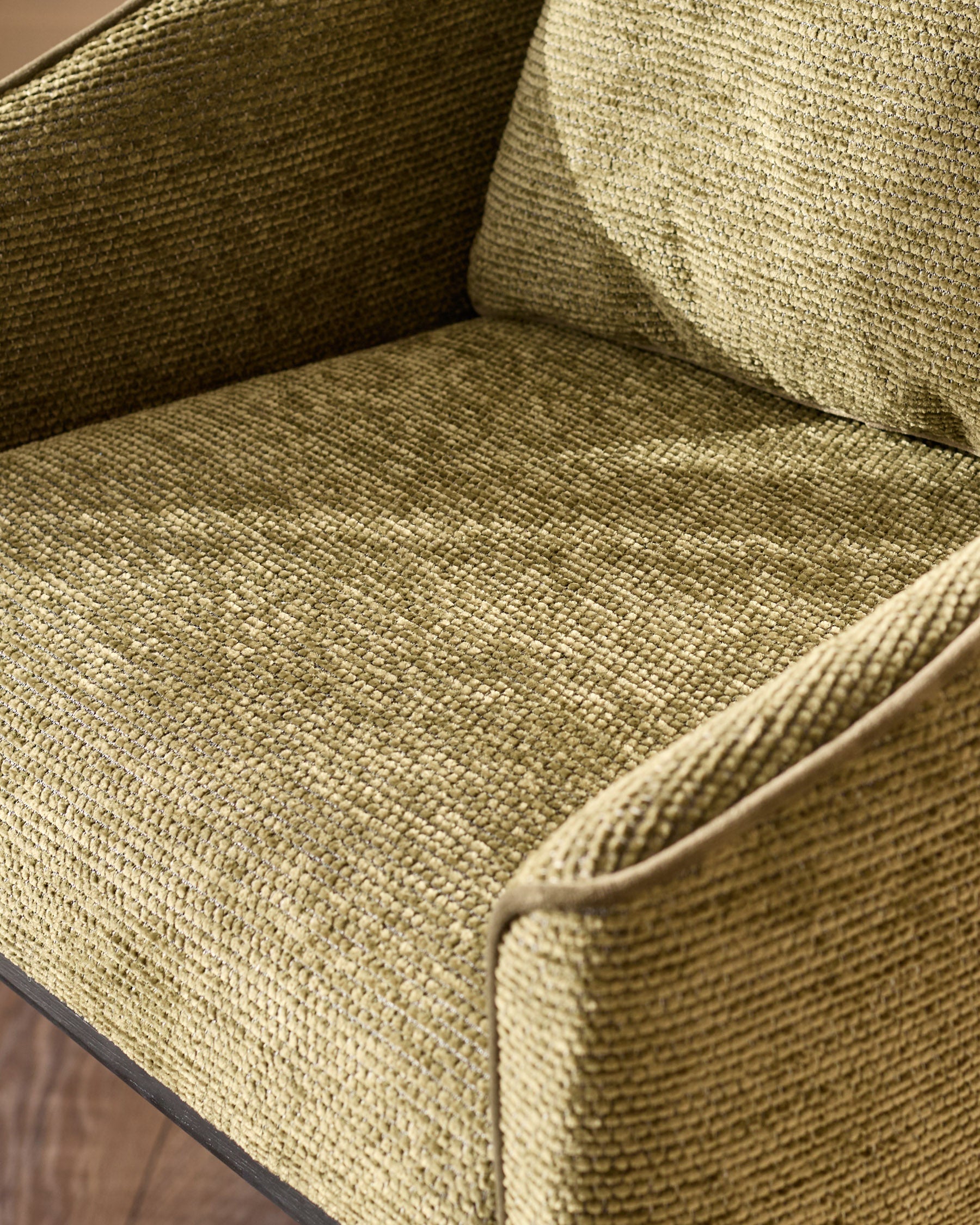 Olive green upholstered chair seat and back with textured fabric weave and dark wooden frame detail visible.