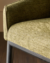 Julep bar stool in olive green fabric, close-up detail of curved backrest and seat with textured weave, dark wood frame.