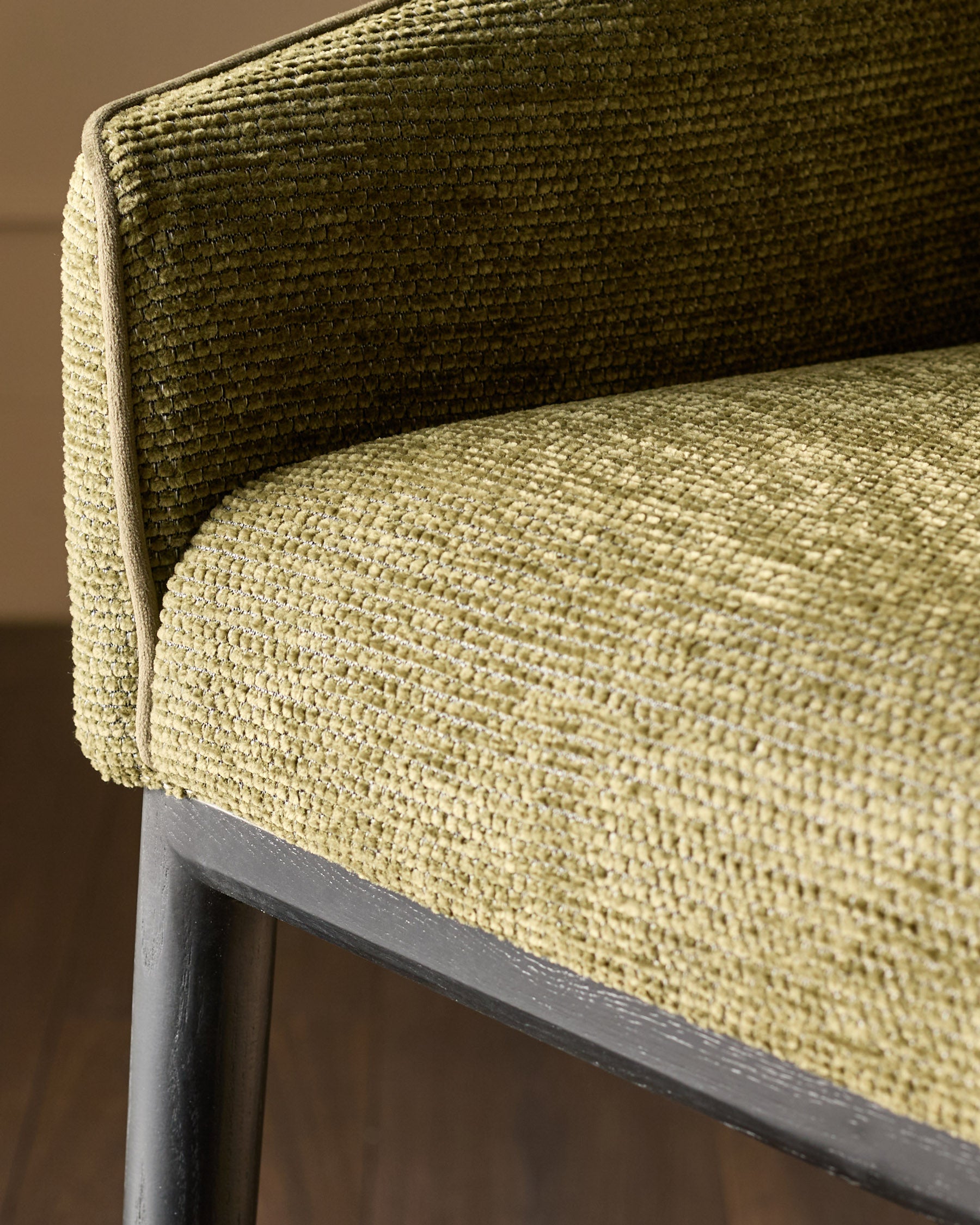 Julep bar stool in olive green fabric, close-up detail of curved backrest and seat with textured weave, dark wood frame.