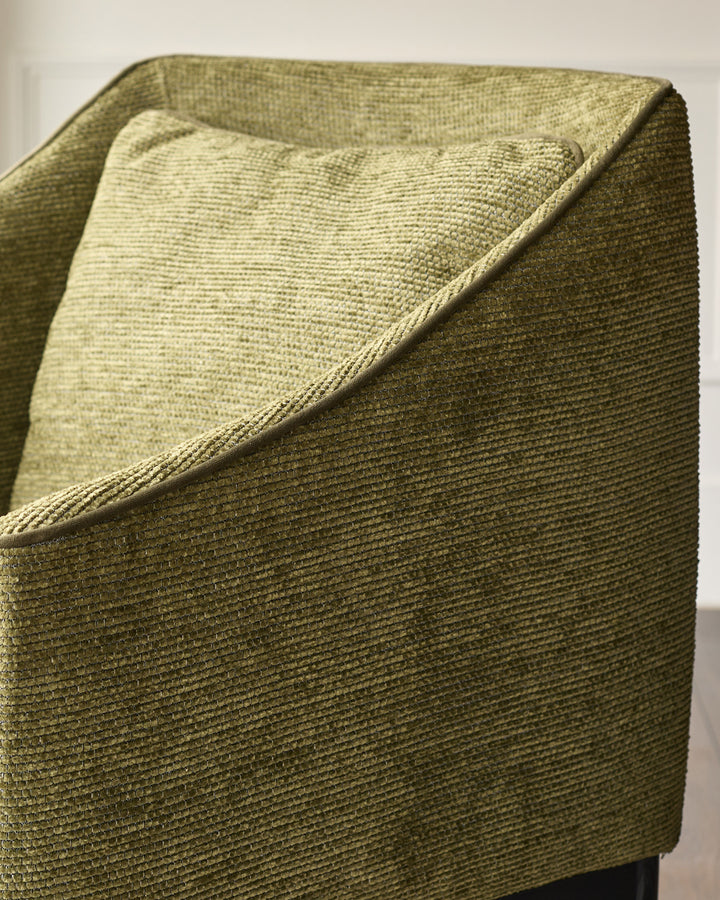 Julep dining chair in olive green fabric, shown at close-up angle highlighting textured weave and curved armrest detail.