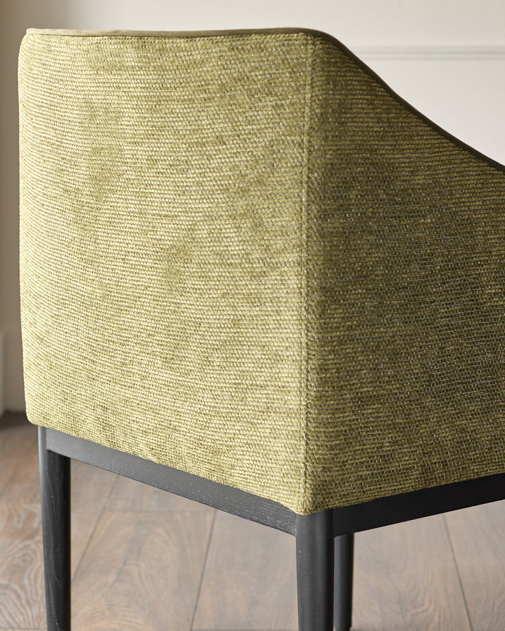 Julep dining chair in olive green fabric, shown at side angle highlighting textured upholstery and black wooden legs.