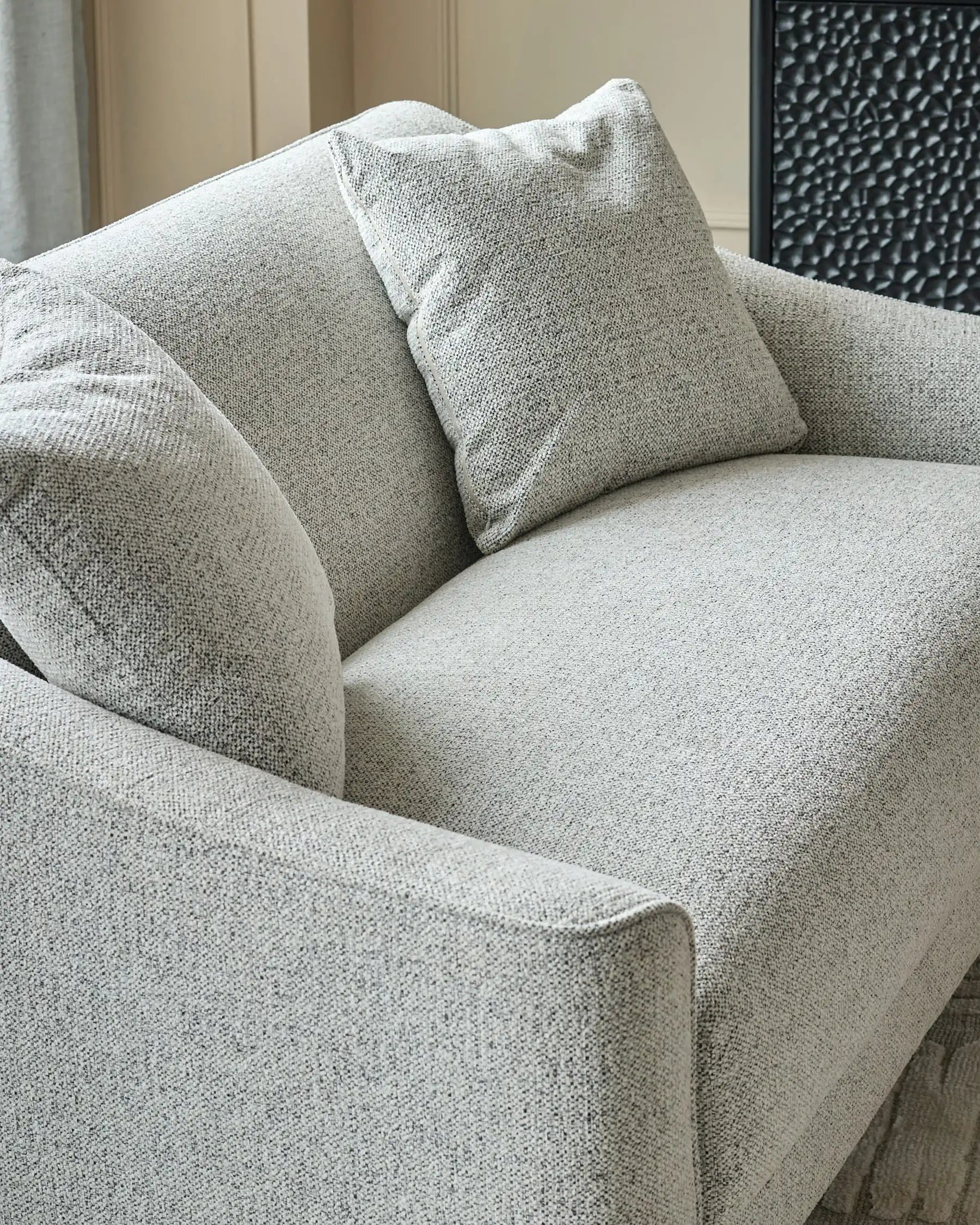 Grey fabric 2-seater sofa with curved armrests and decorative throw pillows, angled side view.