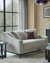 Julep grey fabric 2-seater sofa with black wooden legs, styled in a modern living room setting with pillows and side table.