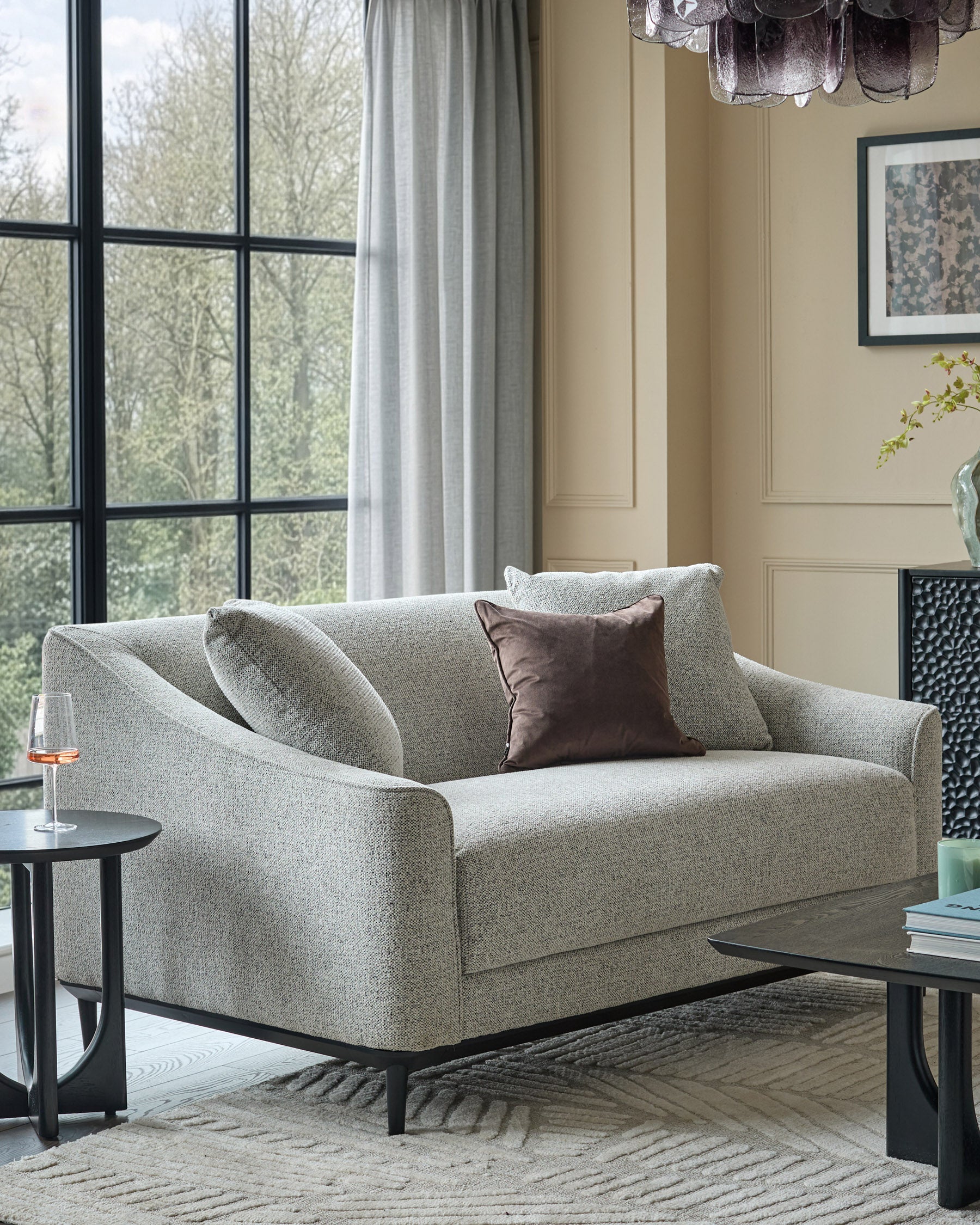 Julep grey fabric 2-seater sofa with black wooden legs, styled in a modern living room setting with pillows and side table.