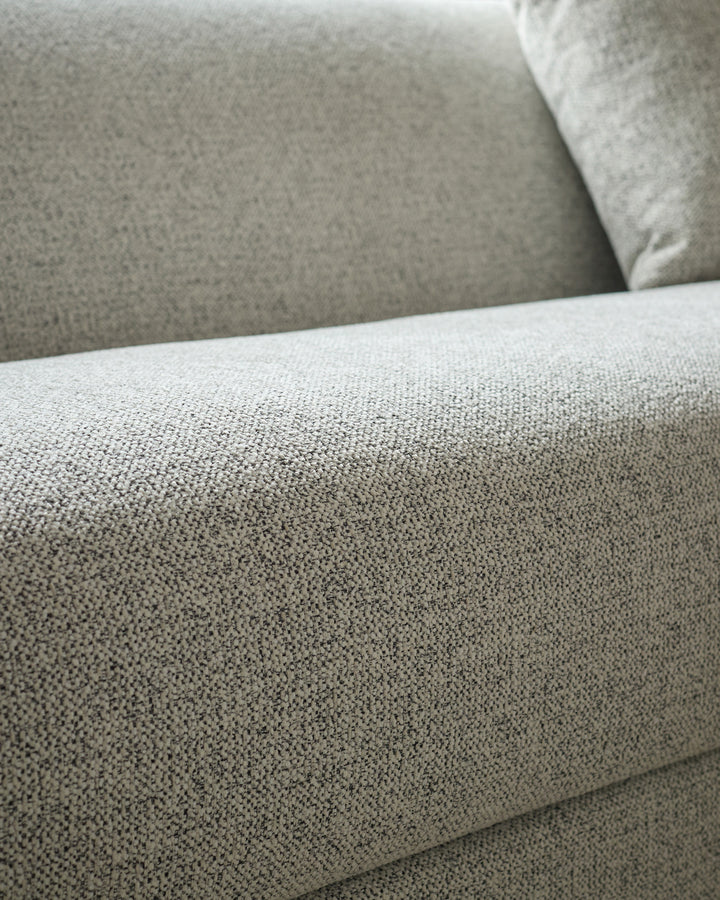 Close-up of grey fabric texture on Julep Blackwood 3-seater sofa, showing woven upholstery detail and cushioned armrest.