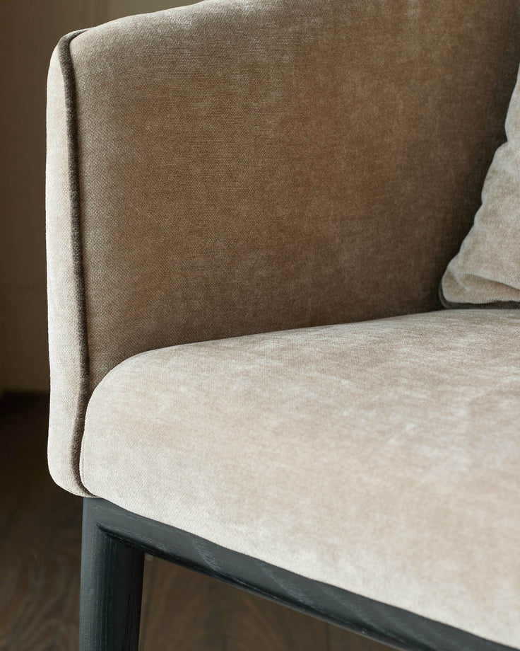 Julep dining chair in champagne fabric, showing curved backrest and seat detail with dark wooden legs.