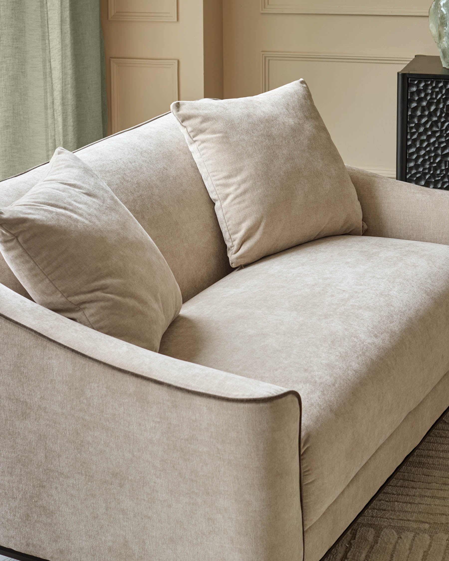 Champagne fabric 2-seater sofa with curved arms, piped edging, and coordinating throw pillows in an elegant interior setting.