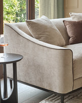 Julep Blackwood 2-seater sofa in champagne fabric, shown at an angle with decorative pillows and wooden legs.