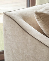 Champagne fabric 2-seater sofa arm detail, showing textured upholstery and tailored seaming against window background.