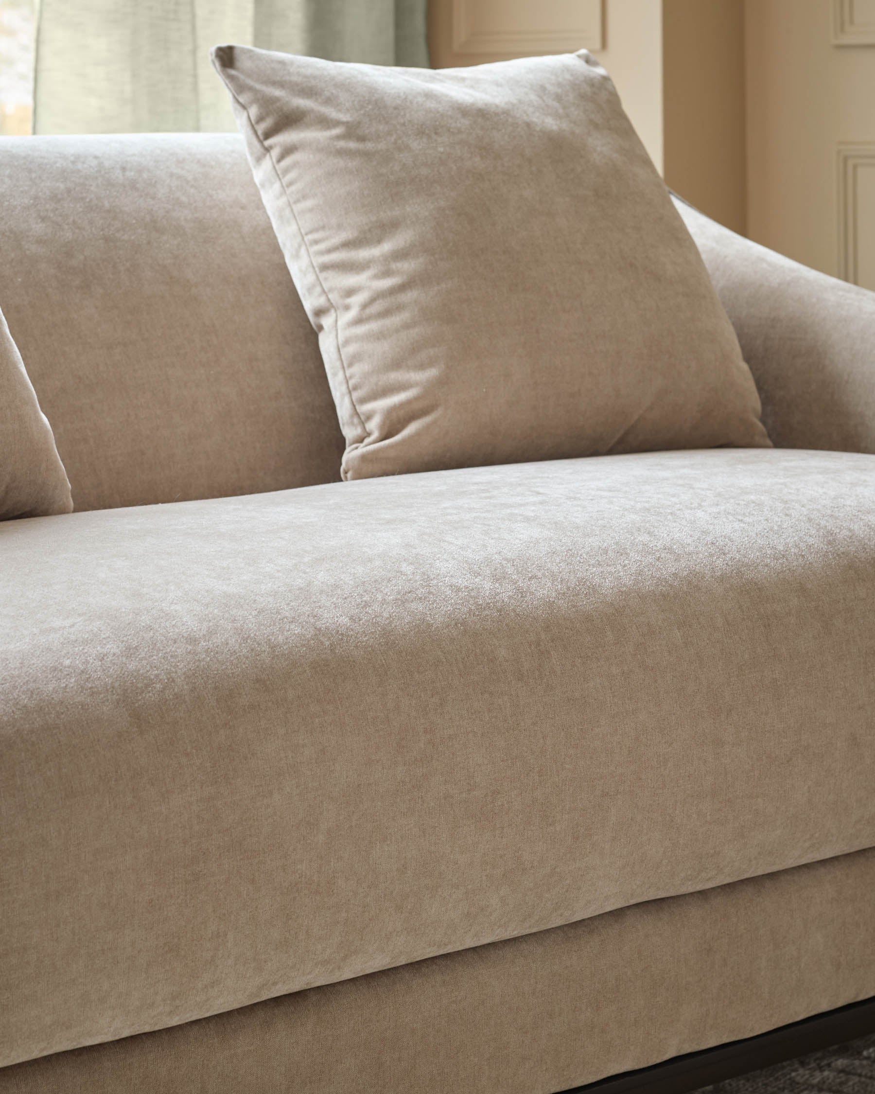 Champagne fabric 2-seater sofa with cushioned back and seat, featuring a coordinating throw pillow.