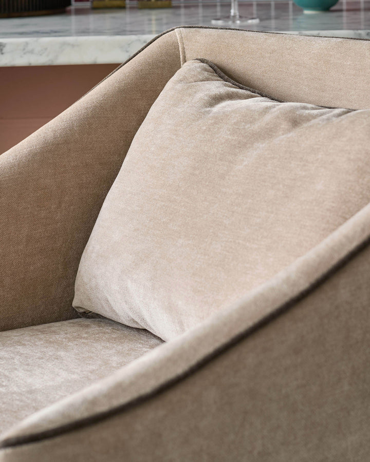 Beige upholstered chair with cushion, close-up detail of fabric texture and curved armrest.