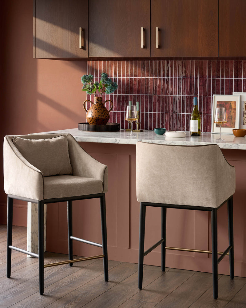 Champagne fabric bar stool with black metal frame and footrest, shown in kitchen setting.