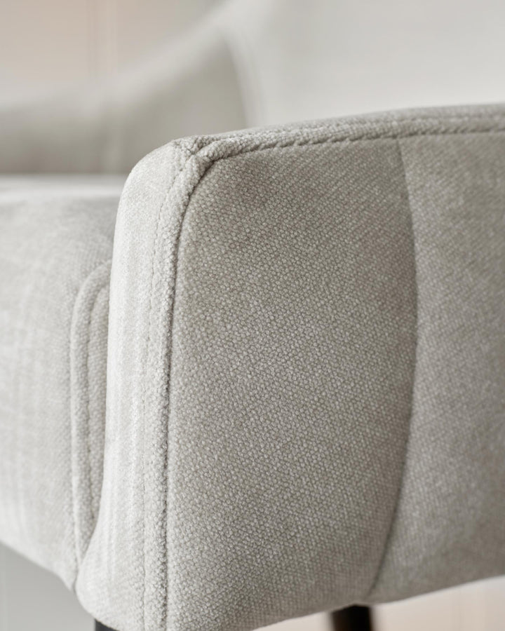 Close-up of a grey, textured armchair, showcasing the fabric detail and quality craftsmanship.