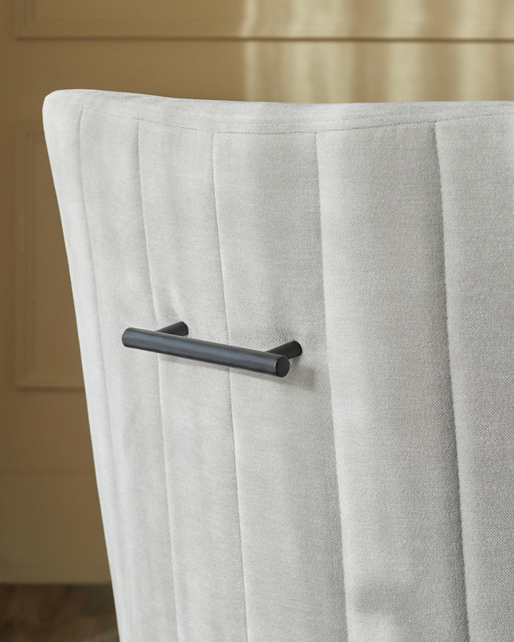 Close-up of a grey upholstered chair, featuring a black handle on its back. Neutral, modern design.