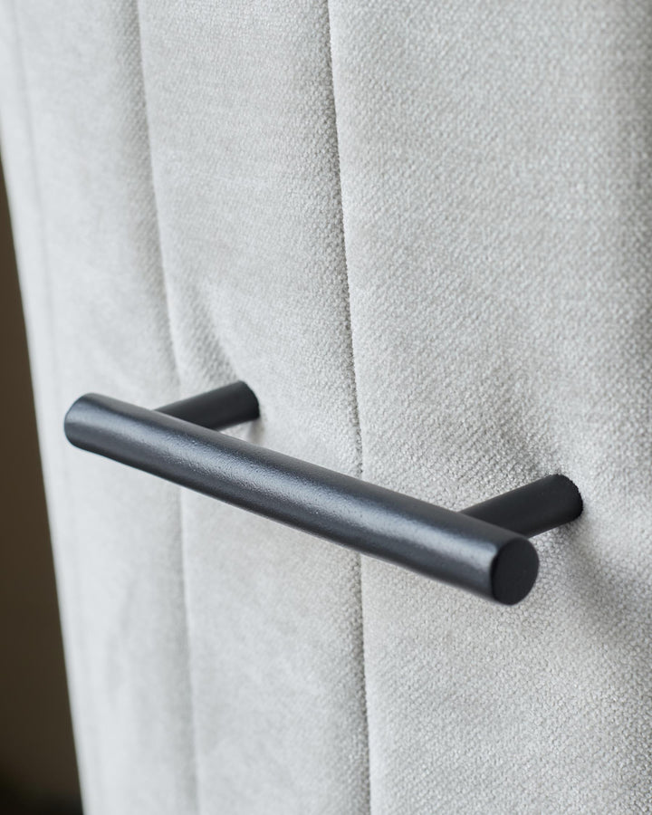 Close-up of a stylish grey upholstered chair with a sleek, modern black handle.