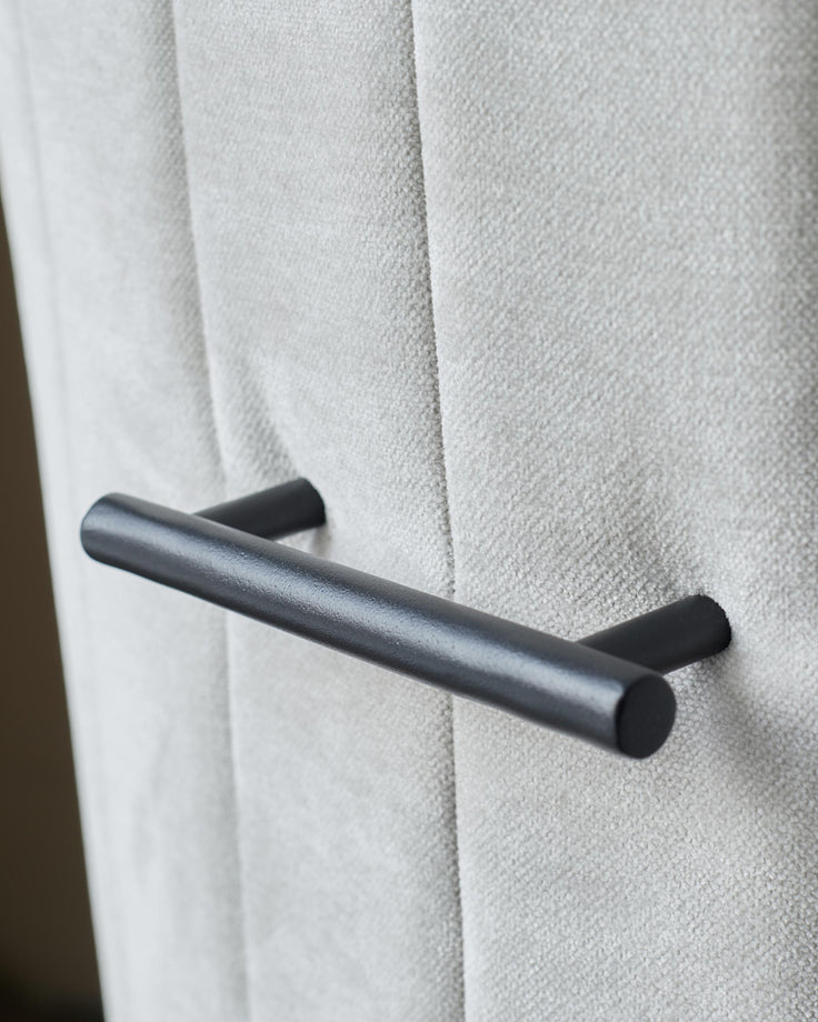 Close-up of a stylish grey upholstered chair with a sleek, modern black handle.