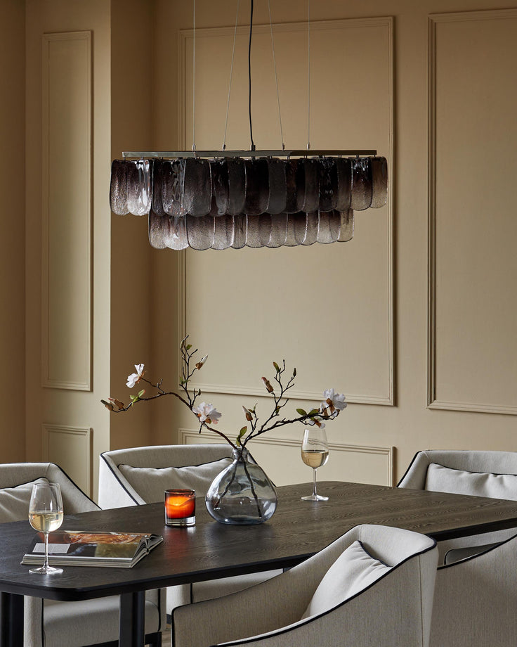 Dining room set with a dark wood table, beige chairs with black trim and a decorative chandelier hanging above.