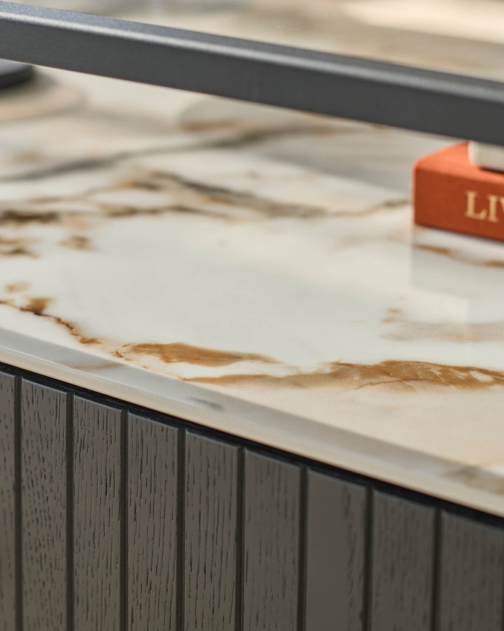 Close up of furniture with a marble top and dark grey wooden base with vertical lines.