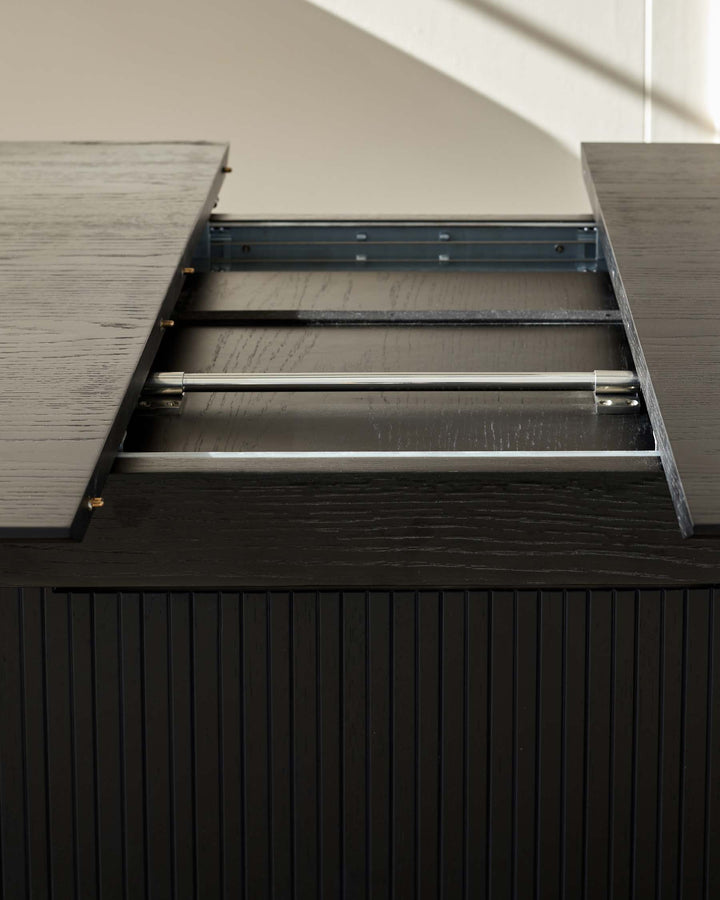 Close-up of a dark wooden extendable dining table showing the extending mechanism.