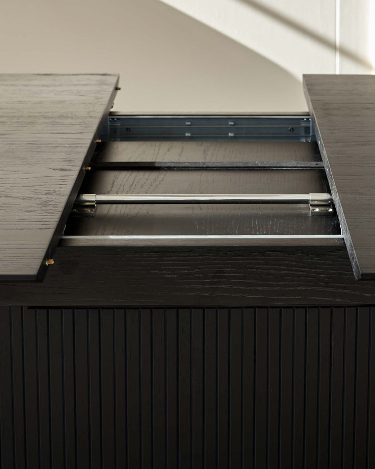 Close-up of a dark wooden extendable dining table showing the extending mechanism.