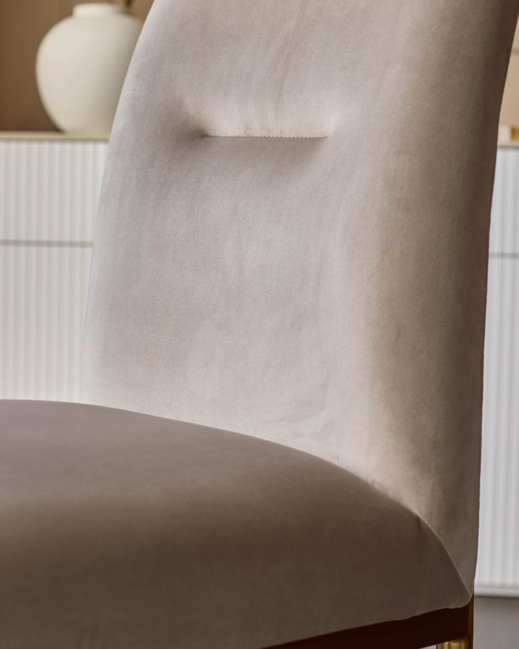 Keira velvet dining chair in champagne, side view showing curved backrest and plush upholstery detail.