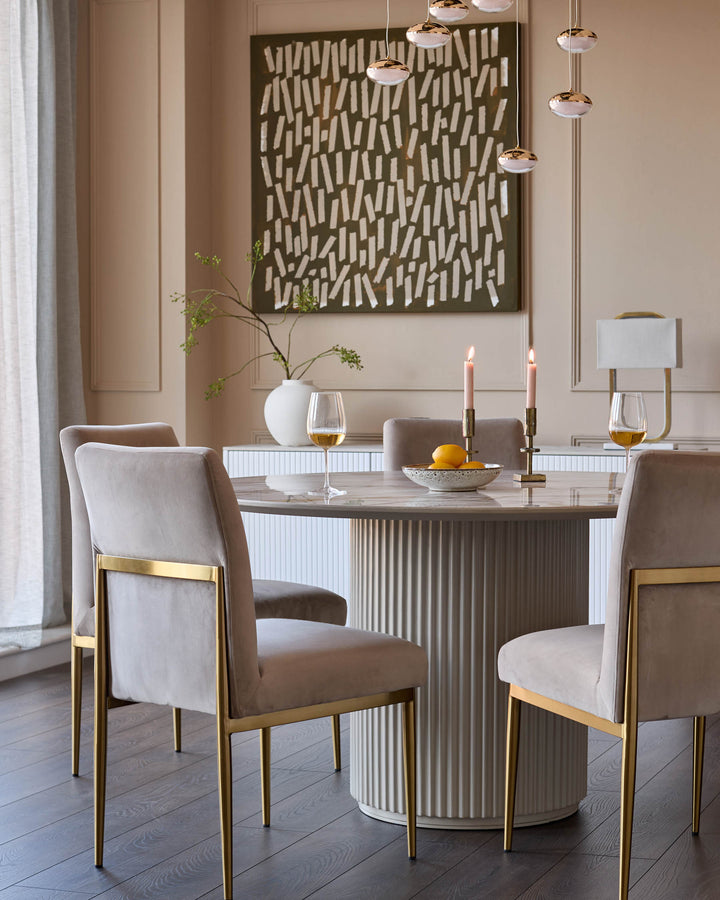 Keira champagne velvet dining chair with brass frame, shown in elegant dining room setting.