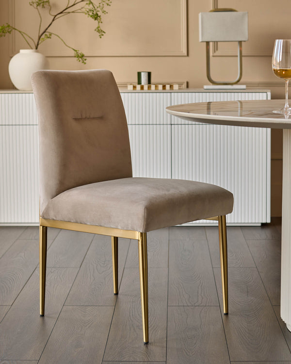Champagne velvet dining chair with gold metal legs, shown in a modern dining room setting.