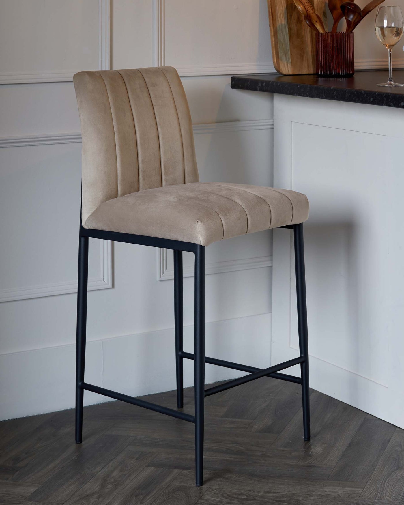 Modern velvet upholstered bar stool with vertical channel tufting on the backrest and a cushioned seat, featuring a sturdy black metal frame with four legs and interconnected footrests.